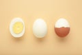 Whole white egg and halved boiled egg with yolk on beige background Royalty Free Stock Photo