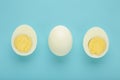 Whole white egg and halved boiled egg with yolk on blue background Royalty Free Stock Photo