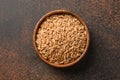 Wholegrain spelt farro in wooden bowl on brown background. Top view