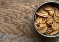 Wholemeal Cornflakes close-up in bowl on wooden background with copy space, useful breakfast whole grain corn flakes