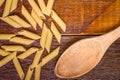 Wholemeal Pasta. Integral Penne into a brown bowl ith a wooden spoon over a wooden table Royalty Free Stock Photo