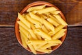 Wholemeal Pasta. Integral Penne into a brown bowl ith a wooden spoon over a wooden table Royalty Free Stock Photo