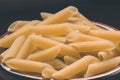 Wholemeal Pasta. Integral Penne into a brown bowl ith a wooden spoon over a wooden table Royalty Free Stock Photo