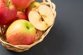 Wholes, one half of red fresh ripe apples full of vitamins lies in wooden wicker basket