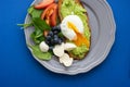 Wholesome tasty full of vitamins and health breakfast with avocado, berries, cheese and tomatoes with basil.