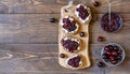 Wholewheat toasts with ricotta and homemade sweet cherry jam on wooden board and background. Copy space