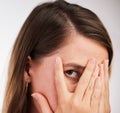 Whos peeking. Studio shot of a young woman covering her face with her hands against a white background. Royalty Free Stock Photo