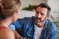 Why didnt you tell me about this. a mature man looking worried while having a discussion with his wife at home.