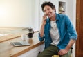 Why dont we meet up for coffee. a man speaking on his cellphone while using his laptop in the kitchen. Royalty Free Stock Photo