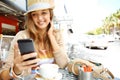 Why dont you join me. A casual young woman sending a text message while sitting at a sidewalk cafe in the city - Royalty Free Stock Photo