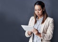 Why not simplify business. Studio shot of a young businesswoman using her tablet against a grey background.