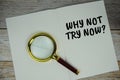 Why not try now? text on note page with magnifying glass top view on wooden background Royalty Free Stock Photo