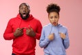 Why us. Shocked disturbed complaining two african american brother sister pointing chest index fingers frowning bothered Royalty Free Stock Photo