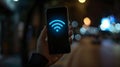 Wi-Fi signal icon on a phone screen held by a hand against a dark background. Royalty Free Stock Photo