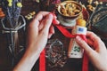 Wiccan witch casting money spell at her altar - tying red ribbon around yellow candle with money banknotes using her hands