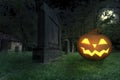 A wicked grinning halloween pumpkin lies in a cemetery