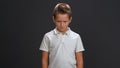 Wicked little boy looking at the camera wearing white polo shirt and black pants isolated on black background