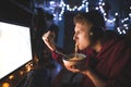 Wicked teen plays video games on a computer and eats fast food. Supper at the computer at night