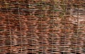 wicker braided wall of willow red rods in the garden of medieval style with supporting poles dividing the flowerbeds of the herb