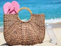 Wicker bag with flip flops on the beach next to a plastic water bottle. background sand Royalty Free Stock Photo