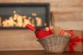 Wicker basket with bottle of wine and gift boxes on table in room Royalty Free Stock Photo