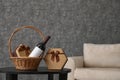 Wicker basket with bottle of wine and gift boxes on table in room. Royalty Free Stock Photo