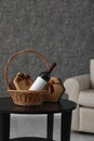 Wicker basket with bottle of wine and gift boxes on table in room Royalty Free Stock Photo