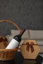 Wicker basket with bottle of wine and gift boxes on table in room Royalty Free Stock Photo