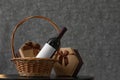 Wicker basket with bottle of wine and gift boxes on table Royalty Free Stock Photo