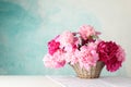 Wicker basket with bouquet of beautiful peonies on white table against blue background Royalty Free Stock Photo