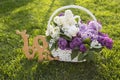 wicker basket with a bouquet of fresh blooming lilacs in white and purple flowers on a green lawn Royalty Free Stock Photo