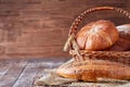 Wicker basket with bread. Bread and buns inside basket. On the wooden table. Royalty Free Stock Photo