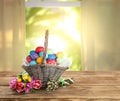 Wicker basket with bright painted Easter eggs and spring flowers on wooden table indoors Royalty Free Stock Photo