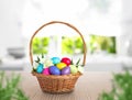 Wicker basket with bright painted Easter eggs and spring flowers on wooden table Royalty Free Stock Photo