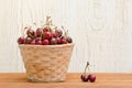 Wicker basket with cherries on a wooden table, empty space Royalty Free Stock Photo