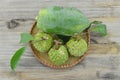 Wicker basket with custard apple and green papaya on wooden table