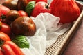 Wicker basket with delicious tomatoes on color table