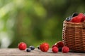 Wicker basket with different fresh ripe berries on wooden table outdoors, space for text Royalty Free Stock Photo