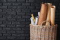 Wicker basket with different rolled papers on dark brick wall background Royalty Free Stock Photo