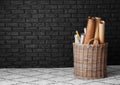 Wicker basket with different rolled papers near dark brick wall indoors Royalty Free Stock Photo