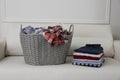 Wicker basket with dirty laundry and stack of clean clothes on sofa indoors Royalty Free Stock Photo