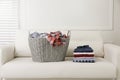 Wicker basket with dirty laundry and stack of clothes on sofa indoors Royalty Free Stock Photo