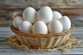 A wicker basket filled with fresh white eggs sits on a rustic wooden surface, surrounded by straw Royalty Free Stock Photo