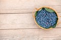 A wicker basket with fresh bilberry (Vaccinium myrtillus) on an old wooden bench. Fresh garden blueberries Royalty Free Stock Photo