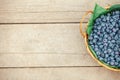 A wicker basket with fresh bilberry (Vaccinium myrtillus) on an old wooden bench. Fresh garden blueberries Royalty Free Stock Photo