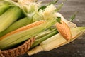 Wicker basket with fresh corn cobs on wooden table, closeup Royalty Free Stock Photo