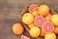 Wicker basket with fresh grapefruits on wooden table, flat lay