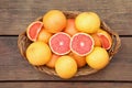 Wicker basket with fresh grapefruits on wooden table, top view