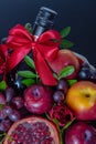 Wicker basket with fruit and a bottle of wine, beautifully decorated on a dark background. concept., congratulations for a holiday Royalty Free Stock Photo