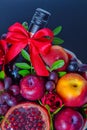 Wicker basket with fruit and a bottle of wine, beautifully decorated on a dark background. concept., congratulations for a holiday Royalty Free Stock Photo